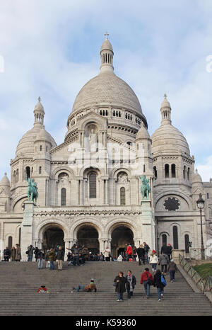 PARIS, FRANCE - January 05; Famous Sacre Coeur basilica with people walking around and seating on the stone stairs in Paris, France - January 05, 2010 Stock Photo