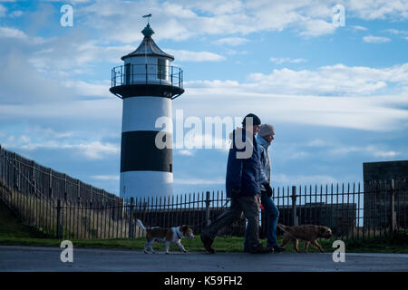 Dog walkers dressed in cold weather clothes walking past Southsea Castle in Portsmouth Stock Photo