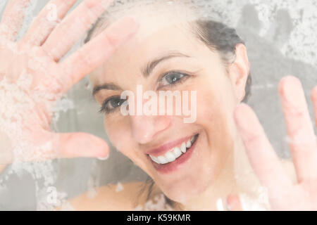 Close-up portrait of a woman having fun touching the glass in the shower Stock Photo