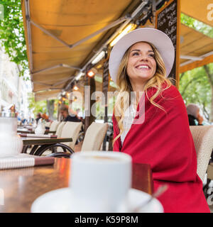 attractive young woman sits with a cute pug in the arms in a street cafe Stock Photo