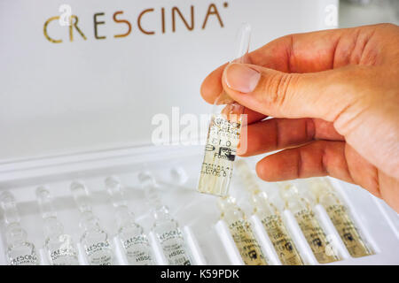 Paphos, Cyprus - November 13, 2015 Woman hand with ampoule of Crescina Re-Growth in front of Crescina treatment box. Shallow depth of field. Crescina  Stock Photo