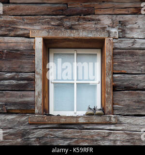 Window with shoes on windowsill in old wooden house, Livigno, Italy Stock Photo