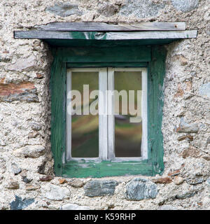 Wall with old window in green wooden frame, Livigno, Italy Stock Photo
