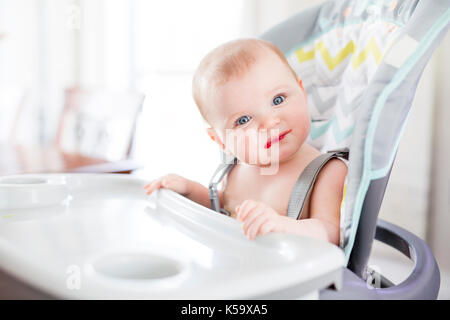 Baby girl sitting in high chair for eating Stock Photo
