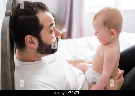 Young happy father playing with babyon bed Stock Photo