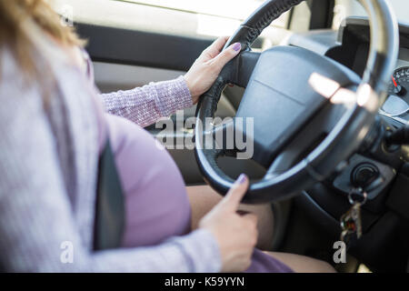 pregnant woman driving a car buttoned up belt Stock Photo