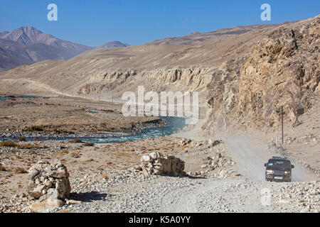 4WD vehicles driving on the Pamir Highway / M41 along the Pamir River in the Gorno-Badakhshan province, Tajikistan Stock Photo