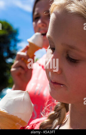 Closeup of an ice cream cone, melting, happy blonde kid child Stock Photo