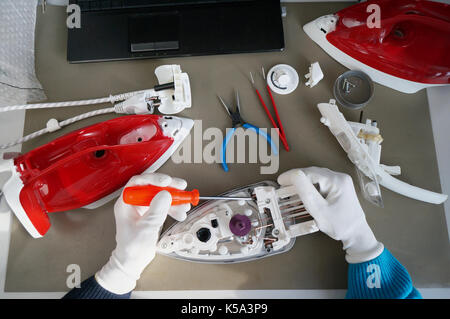 Repair of the mass production electrical iron  in the no professional service center.  Top view shot Stock Photo