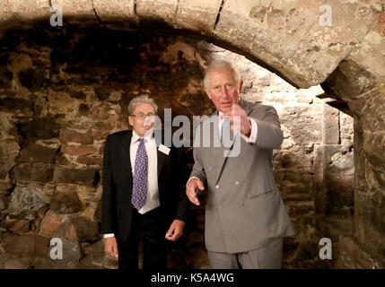 The Prince of Wales, known as the Duke and Duchess of Rothesay while in Scotland, stands inside a fireplace with Mike Cressey from CFA Archaeology during a visit to the Patrick Geddes Centre at Riddle's Court, an A listed 16th Century courtyard house newly restored by Scottish Historic Buildings Trust Stock Photo