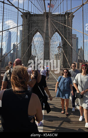 Crowds of tourists walk over Brooklyn Bridge on a sunny Labor Day holiday with Lower Manhattan in the background