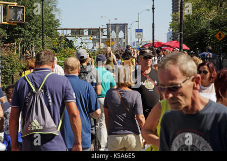 Crowds of tourists walk over Brooklyn Bridge on a sunny Labor Day holiday