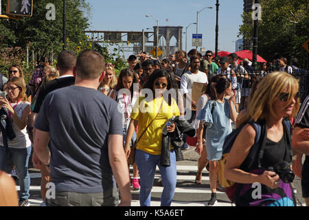 Crowds of tourists walk over Brooklyn Bridge on a sunny Labor Day holiday