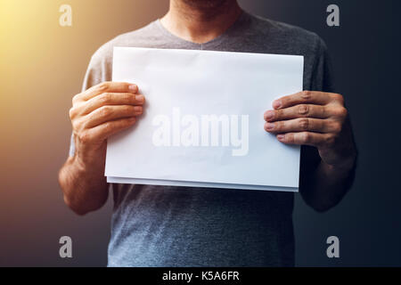 Casual man holding blank A4 paper as mock up copy space for text or graphic design Stock Photo