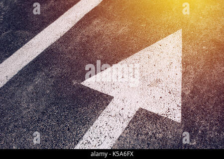 Moving in the right direction, white arrow symbol as traffic sign on asphalt road for motion directing toward the successful future represented by the Stock Photo