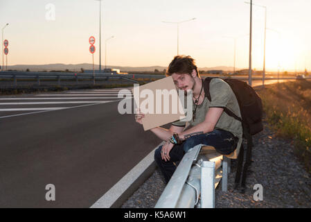 Handsome young man holding cardboard and hitchhikikng Stock Photo