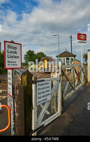 Trains and manually operated level crossing gates at the small Lincolnshire village of Swinderby Stock Photo
