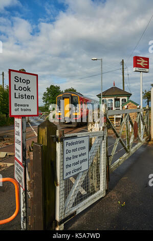 Trains and manually operated level crossing gates at the small Lincolnshire village of Swinderby Stock Photo