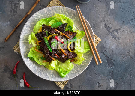 Asian stir-fry liver with bell pepper, carrots and onion. With greens and rice Stock Photo