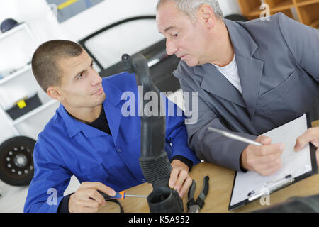 teacher helping student training to be car mechanic Stock Photo