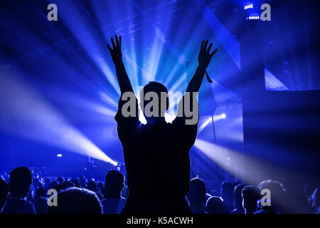 Silhouette of a Woman Dancing Whilst Sat On Someones Shoulders at a Music Concert Stock Photo