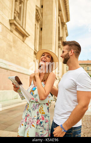 A beautiful young couple are standing and laughing at the St. Stephen’s Basilica in Budapest, Hungary. Stock Photo