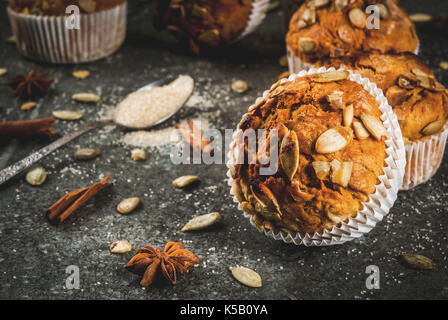 Autumn and winter baked pastries. Healthy pumpkin muffins with traditional fall spices, pumpkin seeds. Black stone table, copy space Stock Photo