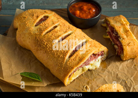 Homemade Cheesy and Meaty Italian Stromboli with Marinara Sauce Stock Photo