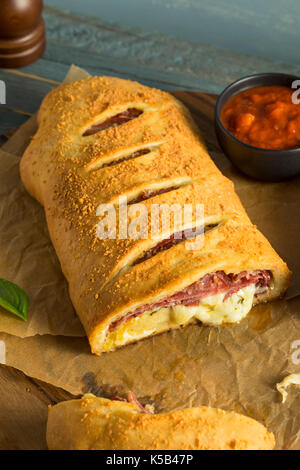 Homemade Cheesy and Meaty Italian Stromboli with Marinara Sauce Stock Photo