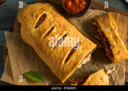 Homemade Cheesy and Meaty Italian Stromboli with Marinara Sauce Stock Photo