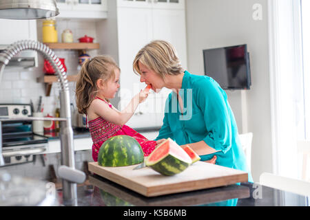 Mother and daughter cut watermelon in kitchen Stock Photo