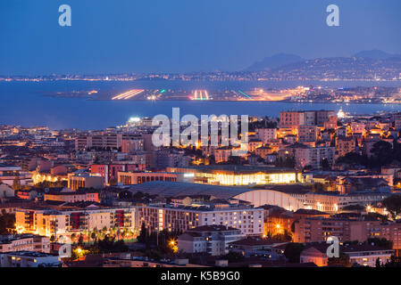 Elevated view of rooftops of Nice at twilight with the airport runways in the distance. French Riviera, Provence-Alpes-Cote d'Azur, France Stock Photo
