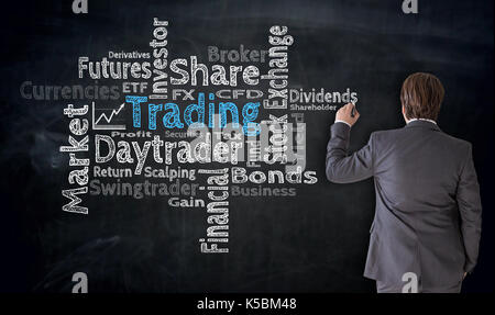 Businessman writes trading cloud on blackboard concept. Stock Photo