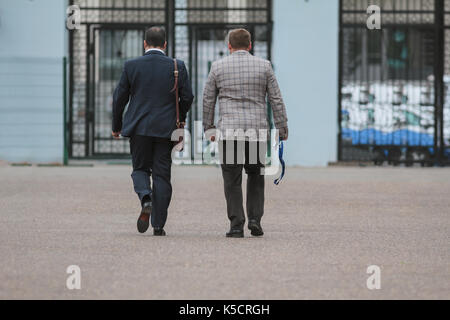 Two businessmen walking along street at conference or exhibition Stock Photo