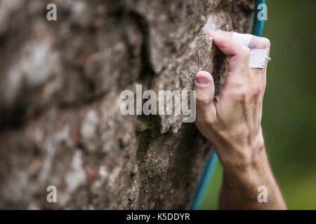 Closeup view of rock climber's hand gripping hold on natural cliff Stock Photo