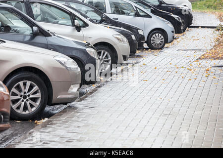 several cars parked in a parking lot on a rainy day Stock Photo