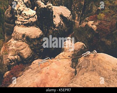 Iron twisted rope fixed in block by screws snap hooks. Detail of rope end  anchored into rock Stock Photo - Alamy