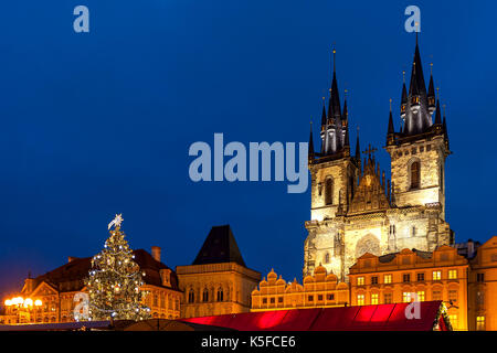 Illuminated Tyn church and Christmas tree on Old Town Square under evening sky in Prague, Czech Republic. Stock Photo