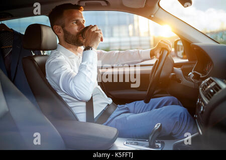 businessman manager driving car while drinking a cup of coffee Stock Photo