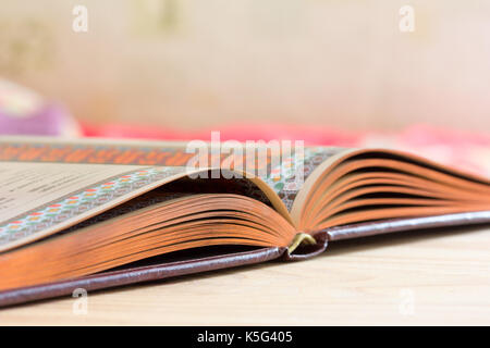 Open book with gilded edge on the table, selective focus and shallow depth of field Stock Photo