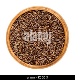 Camargue red rice in wooden bowl. Variety of red wild rice with brownish red colored grains, cultivated in southern France. Isolated macro food photo. Stock Photo