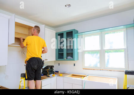 Installation of kitchen. Worker installs doors to kitchen cabinet. kitchen Installation of kitchen cabinet. Stock Photo