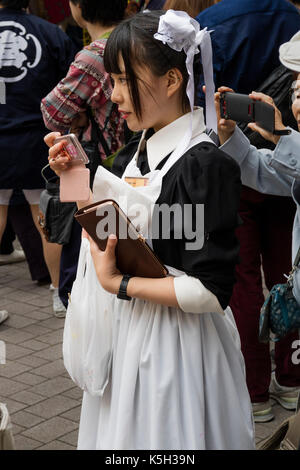 Tokyo, Japan - May 14, 2017: Anime cosplay teenage girl as a maid in the street with her mobile phone Stock Photo