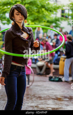 An adolescent girl hula hoops, alone in a crowd, at the drum circle at Pritchard Park in downtown Asheville, NC, USA Stock Photo