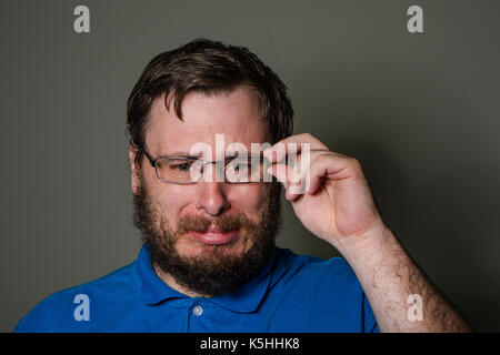 Man removing his glasses while crying Stock Photo
