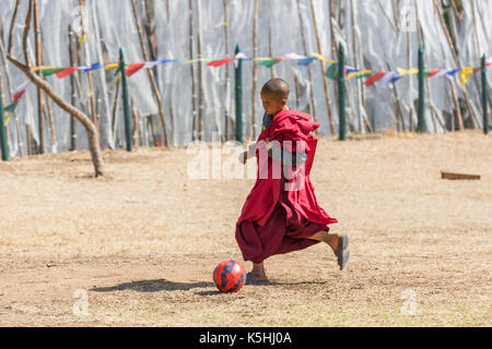 Young monk playing soccer at Chimi Lakhang (temple) near Lobesa, Punakha, Western Bhutan Stock Photo