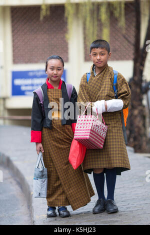 Schoolchildren on their way to the town school wearing traditional Bhutanese costume as uniform in Thimphu, Western Bhutan. Stock Photo