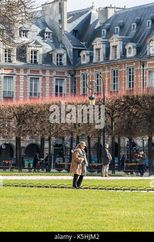 People enjoying the sunshine at Place de Vosges in the Marais, Paris Stock Photo