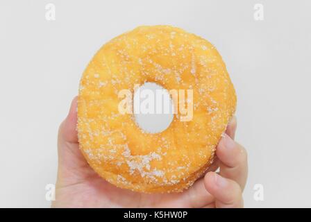 Food and Bakery, Hand Holding Delicious Fresh and Sweet Donut with Sugar Toppings on White Background. Stock Photo