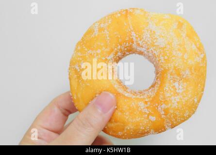 Food and Bakery, Hand Holding Delicious Fresh and Sweet Donut with Sugar Toppings on White Background. Stock Photo